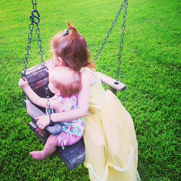 Holding baby sister on swing