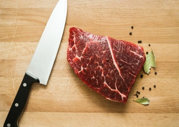 Fresh raw beef on wooden cutting board with  pepper
