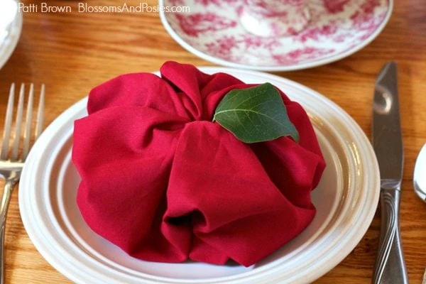 red apple napkin fold on top of a white plate