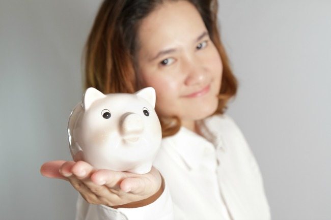 Smiling woman holding piggy bank in hands