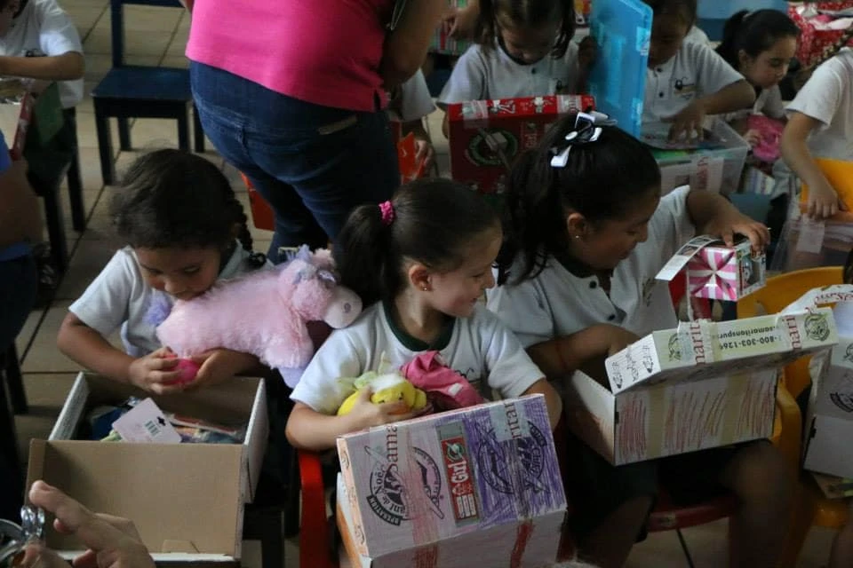 Little girls opening Operation Christmas Child shoeboxes. 