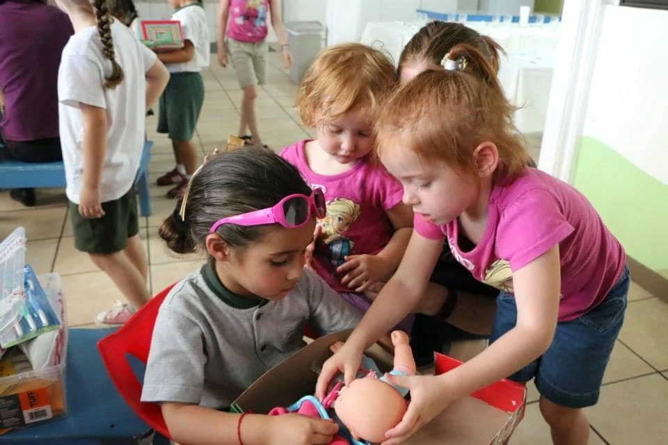 Little girls looking at a baby doll inside an Operation Christmas Child shoebox. 