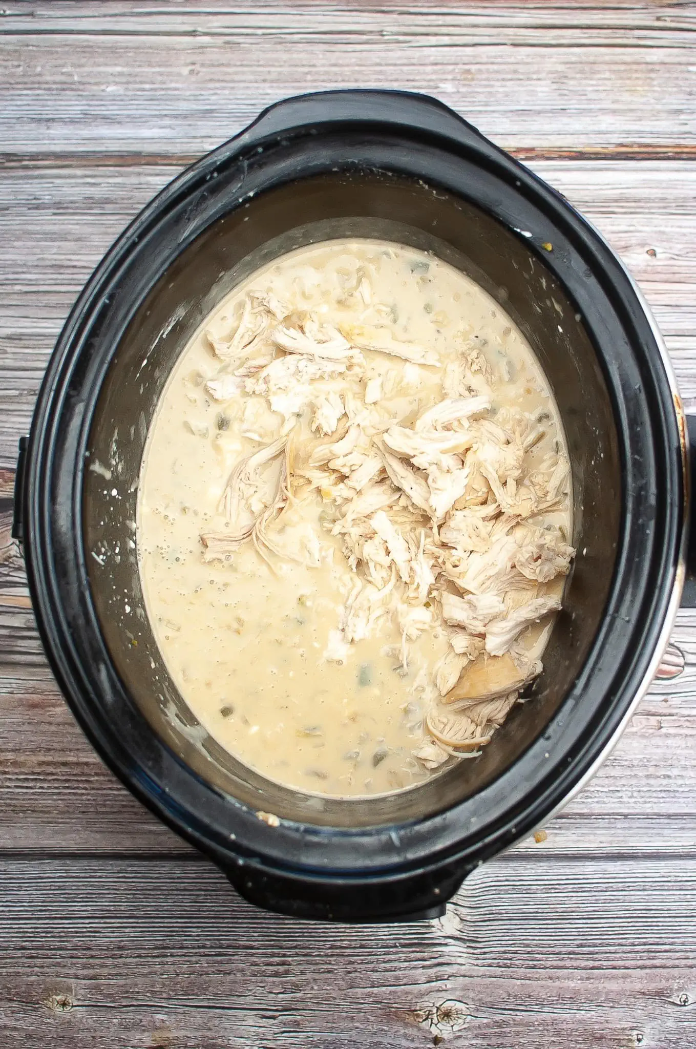 White Chicken Chili in a slow cooker on a wooden table.