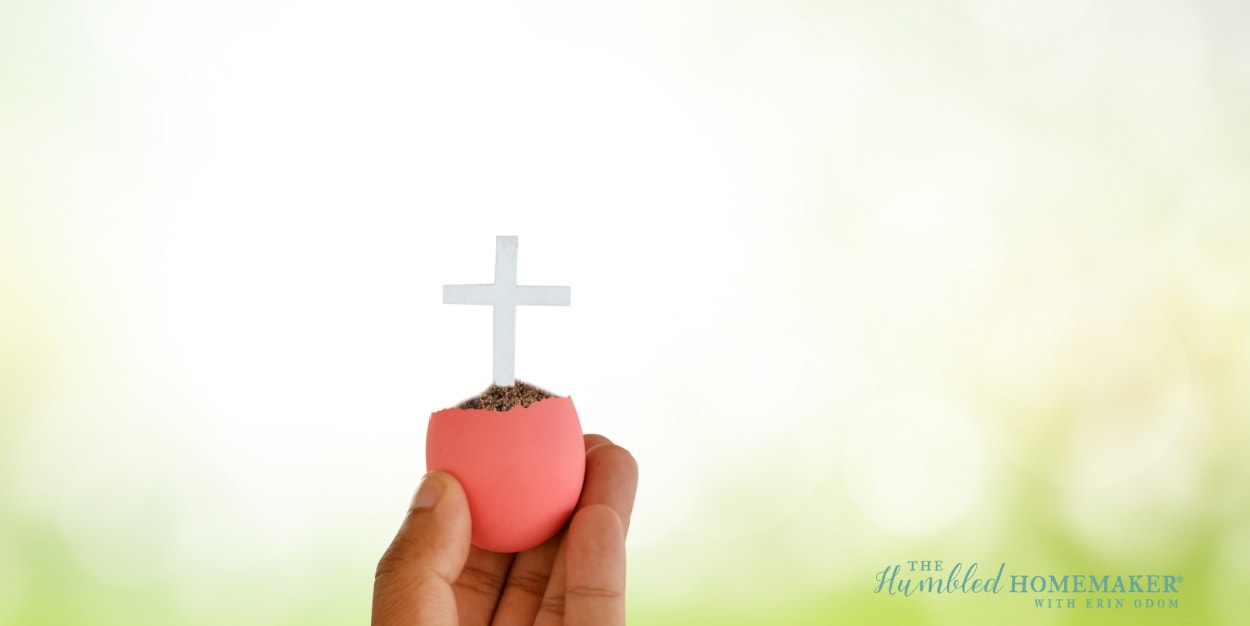 A hand holding a cross in an Easter basket.