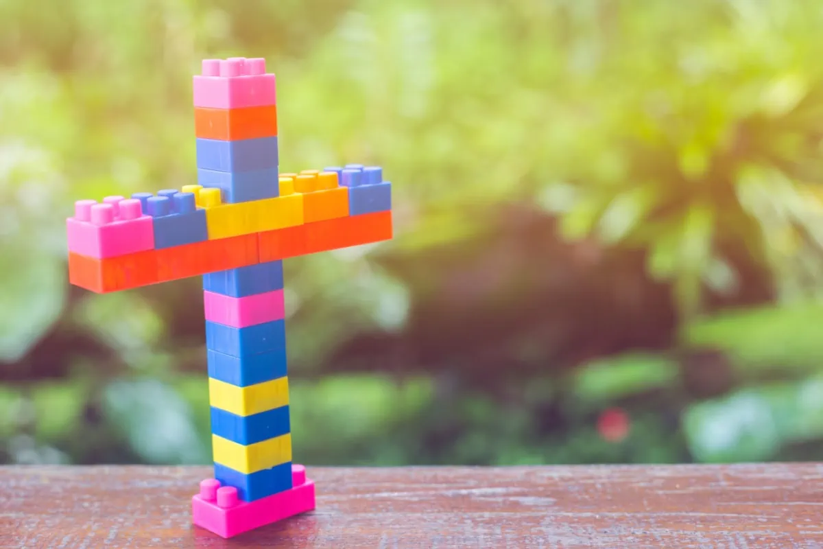 A colorful lego cross on a wooden table, offering spiritual gift ideas.