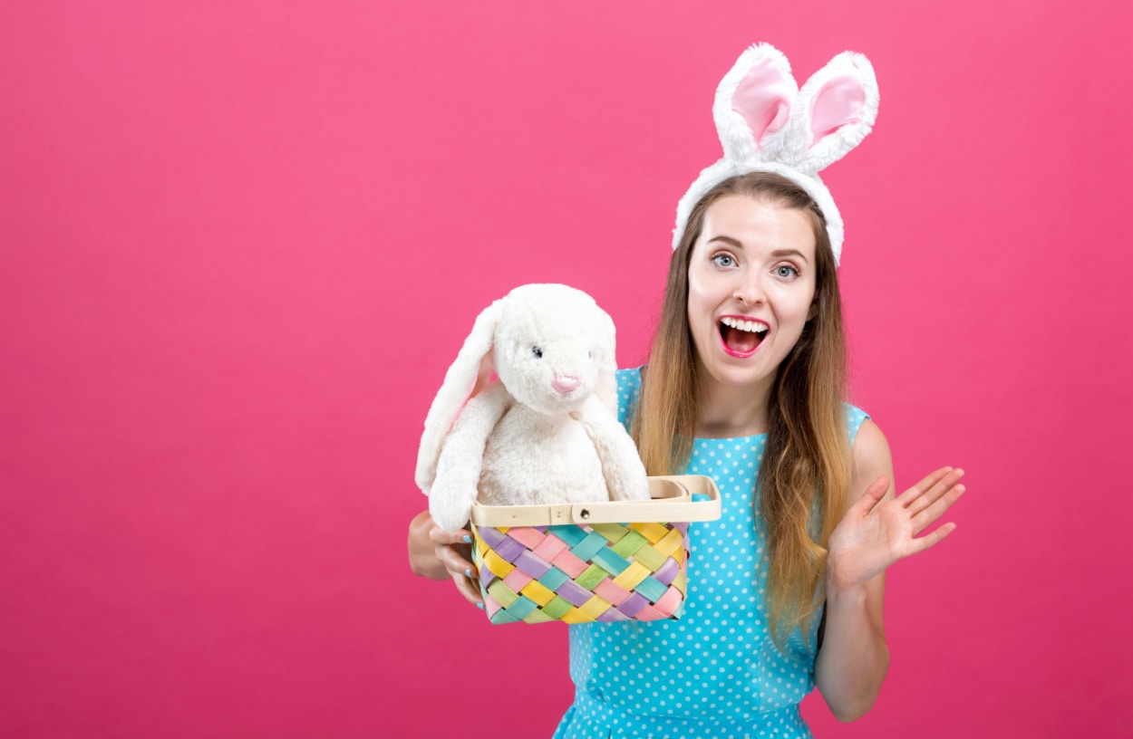 An adorable girl donning bunny ears and clutching a plush bunny to illustrate Easter basket ideas for college students. 