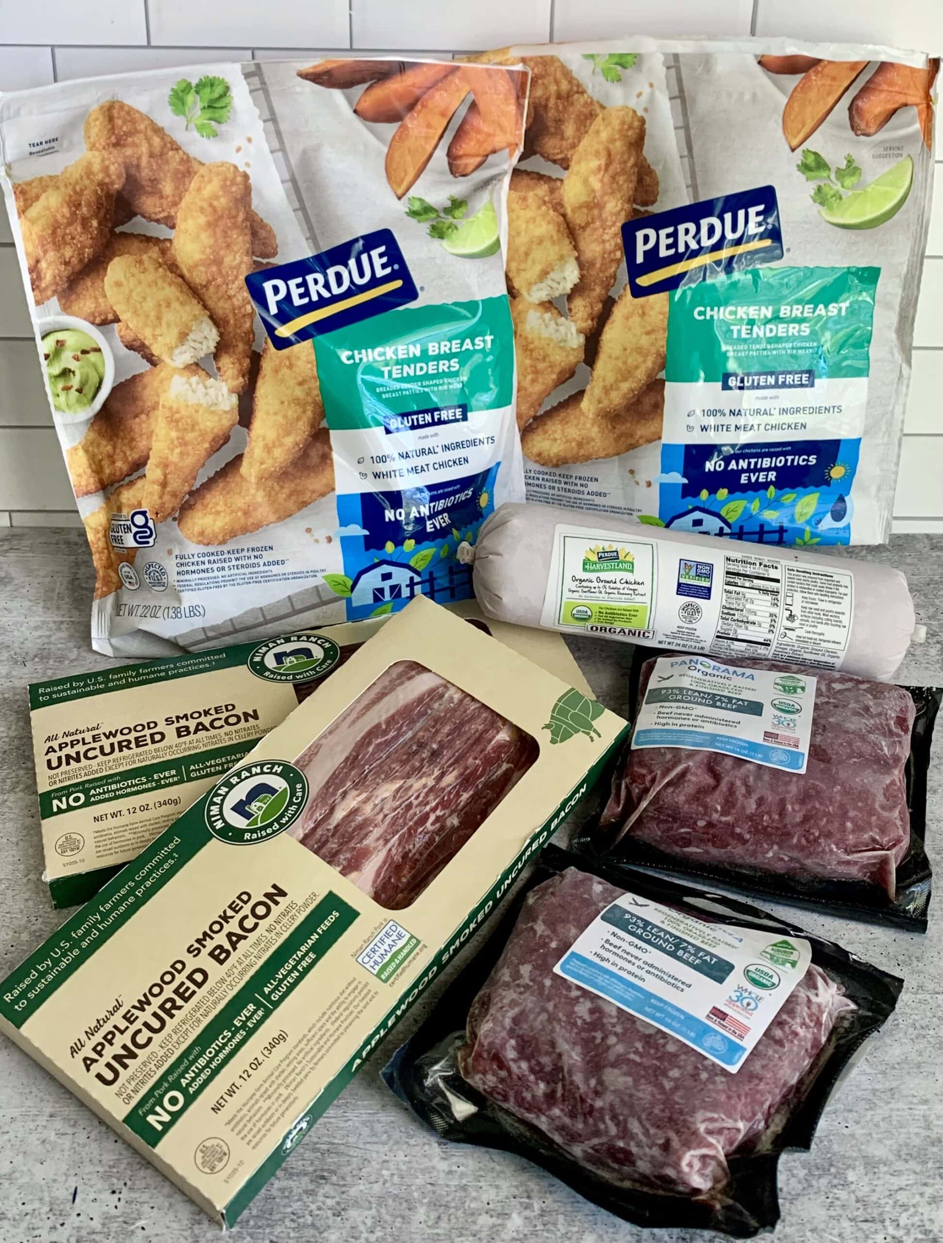 A variety of meat products are shown on a counter to illustrate an honest Perdue Farms review.