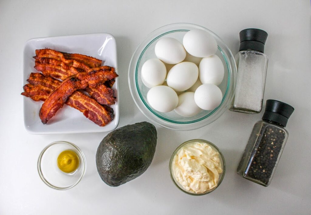 Ingredients for a meal including bacon, eggs, avocado, mayonnaise, oil, salt, and pepper.