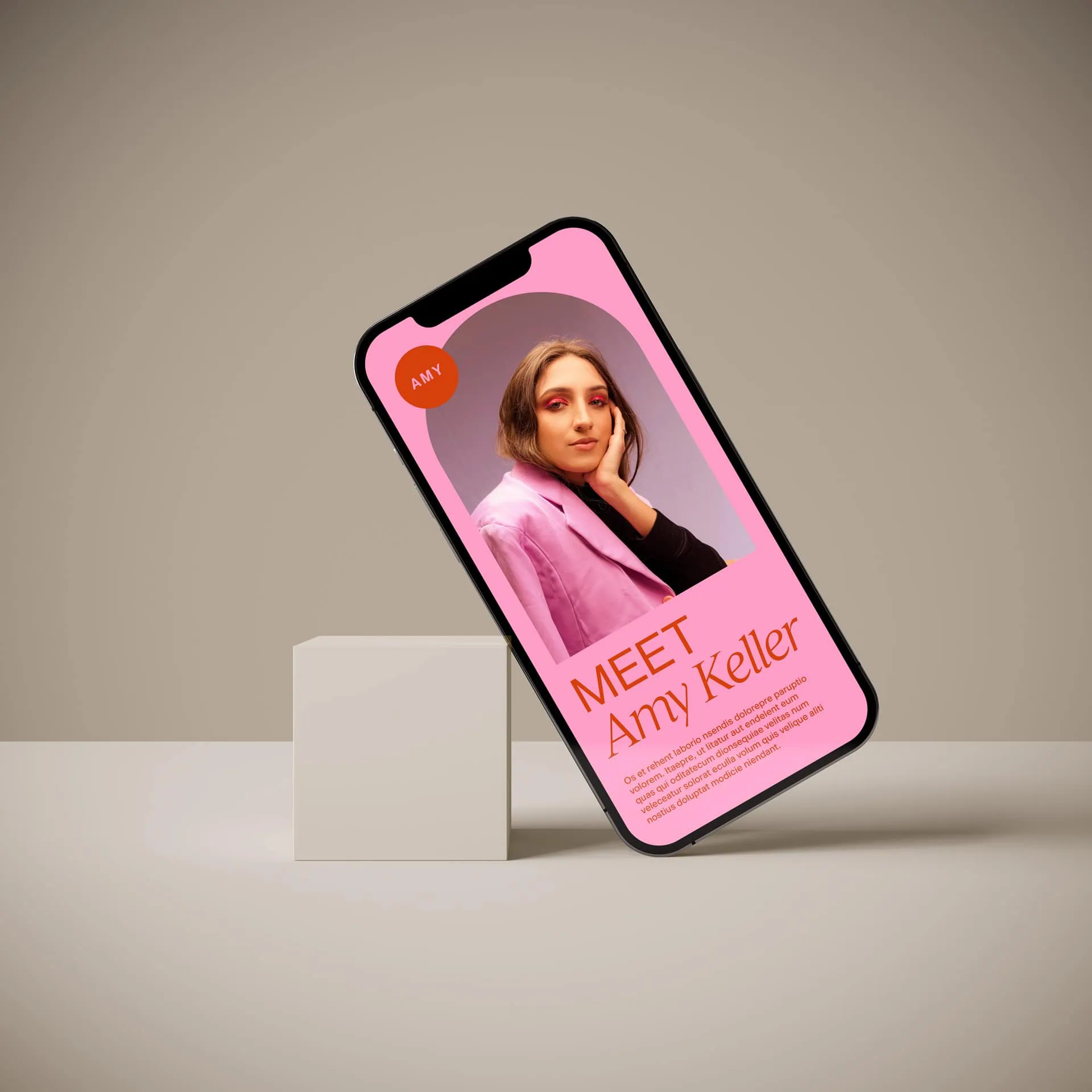 A smartphone displays a profile page with a photo of a woman and text introducing "Amy Keller" on a pink background, propped against a white cube.