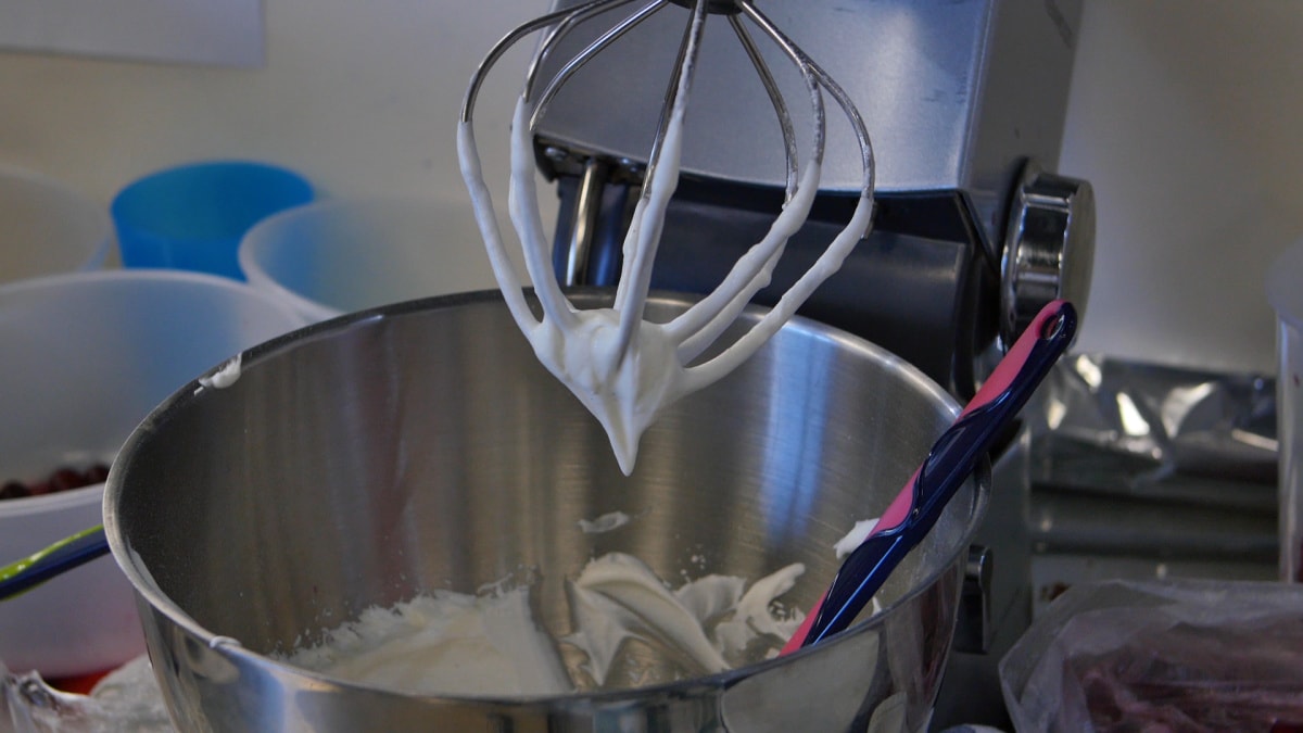A mixer is being used to whip cream into a bowl.
