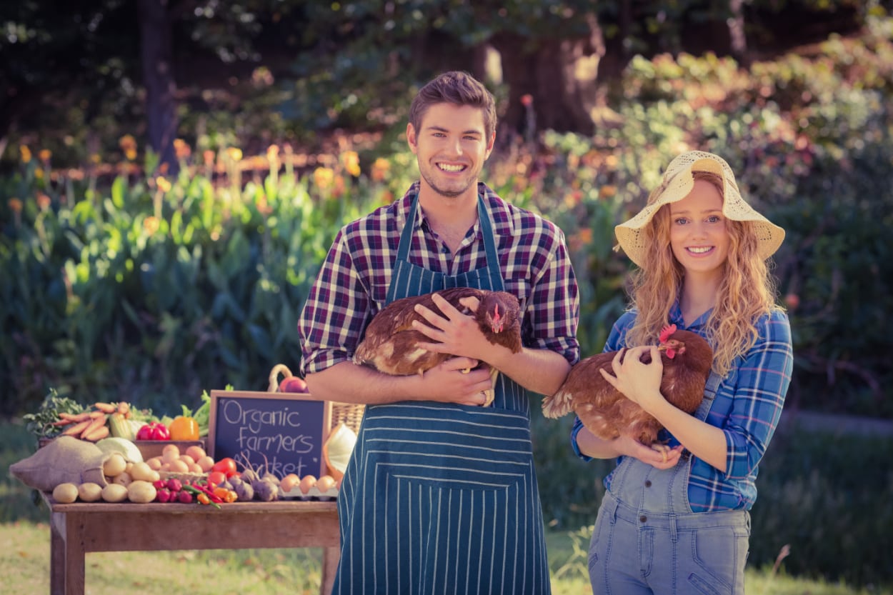 A couple holding chickens in a garden to illustrate a post that gives an honest review of Perdue Farms.