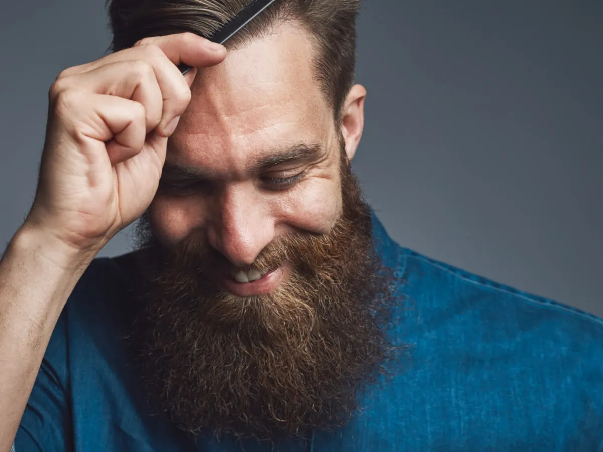 A man with a beard is styling his hair. This man looks like a man who would like Stitch Fix for Men.