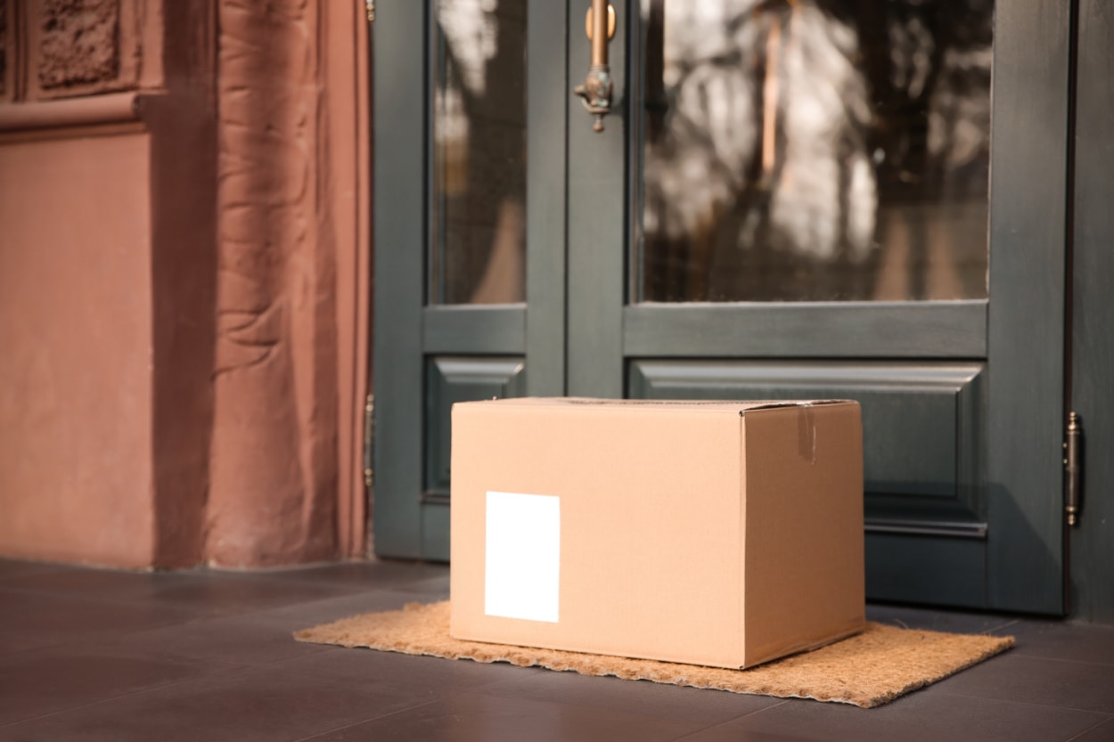 A box of Perdue Farms meat delivery sits on a mat in front of a door.