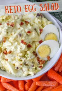 A bowl of keto egg salad with bacon, garnished with slices of boiled eggs, accompanied by a side of baby carrots.