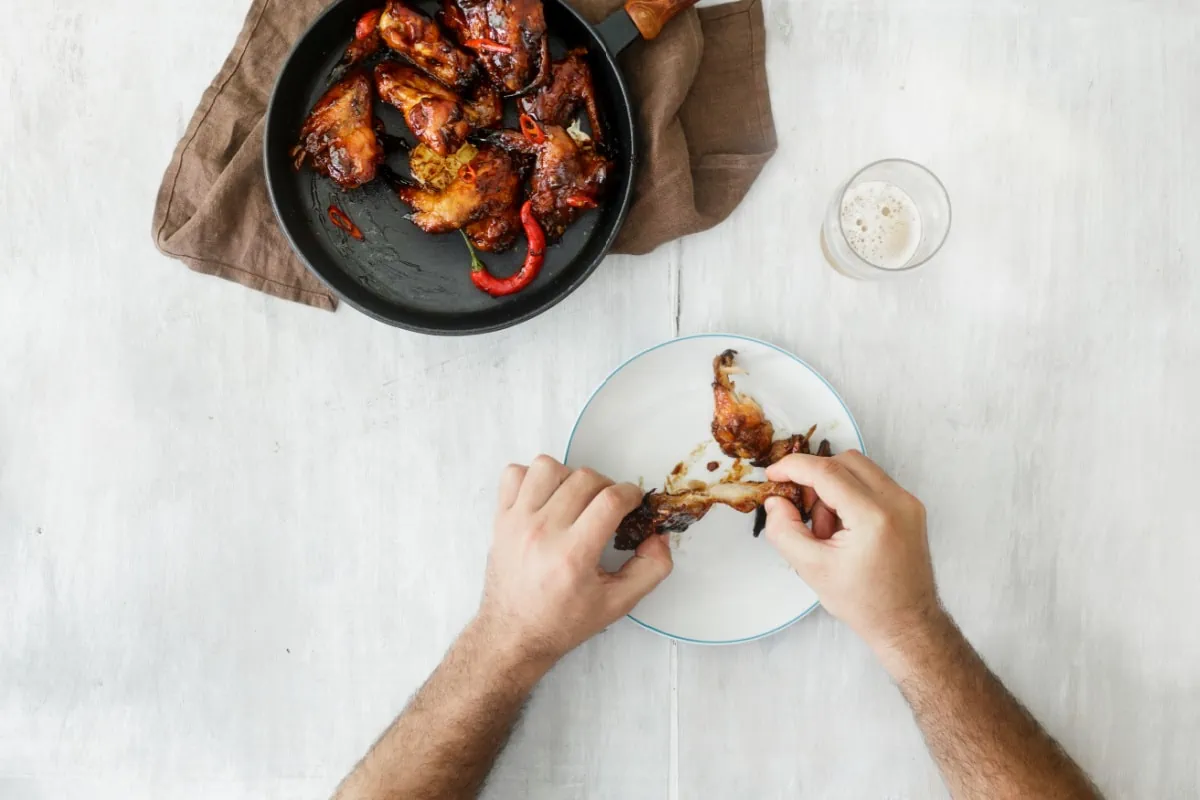 A man is devouring a plate of mouthwatering bbq chicken wings.