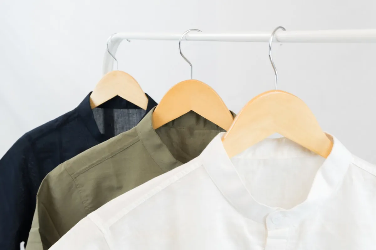 Three white shirts hanging on a wooden rack are part of the Stitch Fix for Men collection.