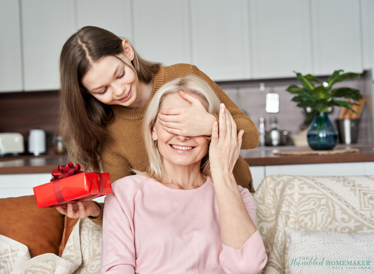 A young woman surprises an older woman with a Mothers' Day gift, playfully covering her eyes.