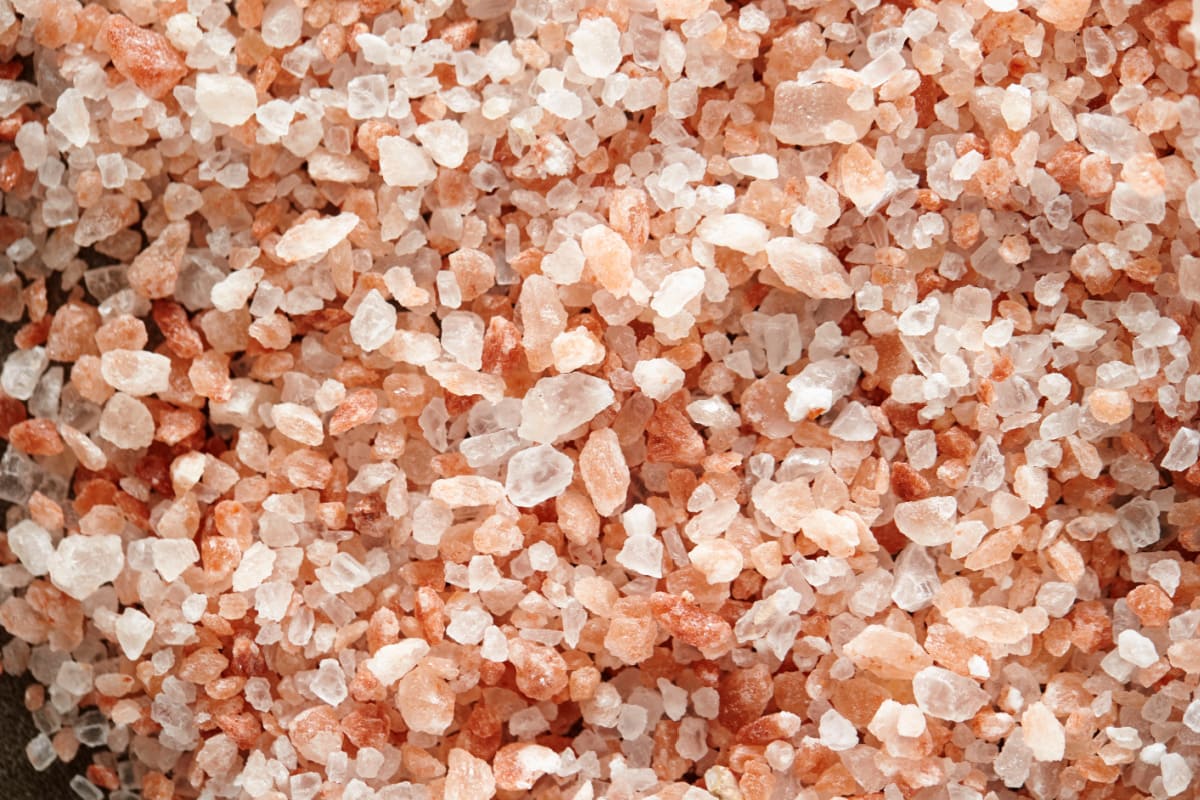 A pile of pink and white salt on a wooden surface.