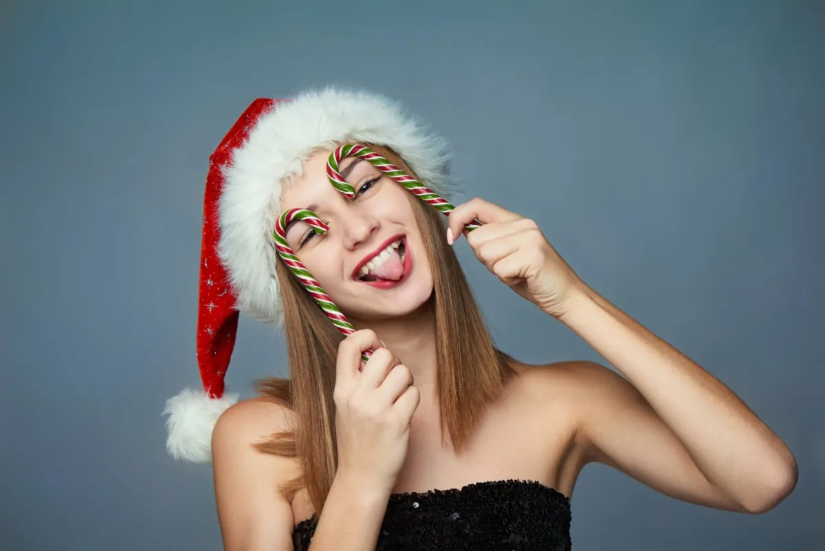 A young woman wearing a santa hat and candy canes.