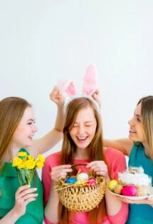 Three young girls with bunny ears holding easter baskets for teenagers.