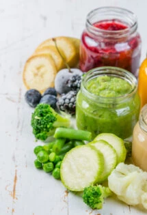 Assorted fruits and vegetables in jars on a wooden table, perfect for baby food purees for use in a blog post on creative ways to use leftover baby food purees.