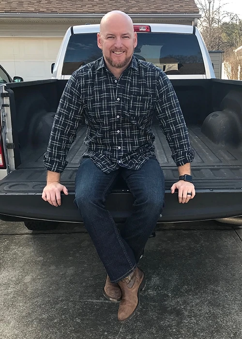 a man modeling clothing from Stitch Fix for Men while sitting on the bed of a truck 